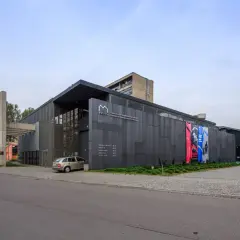 Nowoczesny budynek MOCAK Muzeum Sztuki Współczesnej w Krakowie z betonowym napisem i szarymi panelami.