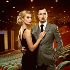 Elegancka kobieta w czarnej sukni i mężczyzna w garniturze, idealnie ubrani do teatru muzycznego.
