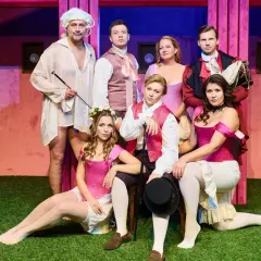 Aktorzy w strojach teatralnych, którzy pracują w teatrze, pozują na scenie.