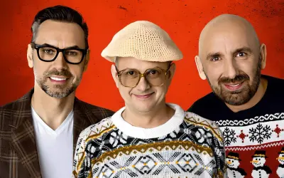 Trzech panów z kabaretu Neo-Nówka w świątecznych swetrach i z uśmiechem na twarzy.