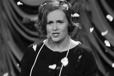 Joanna z kabaretu hrabi, w perłach i z płatkami na głowie, podczas występu.