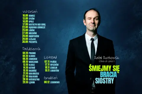 Rafał Rutkowski w czarnym garniturze, mrugając okiem, zaprasza na swój stand-up "Śmiejmy się bracia i siostry".