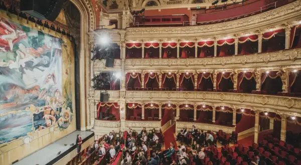 Widownia teatru w Krakowie, gdzie warto iść na spektakl. Złote zdobienia, czerwone aksamitne obicia i wielki malowany kurtyna tworzą magiczną atmosferę.