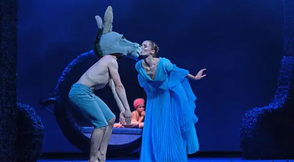 Na scenie, w niebieskim świetle, tancerz w masce osła całuje tancerkę w błękitnej sukni. To magiczny "Sen nocy letniej spektakl".