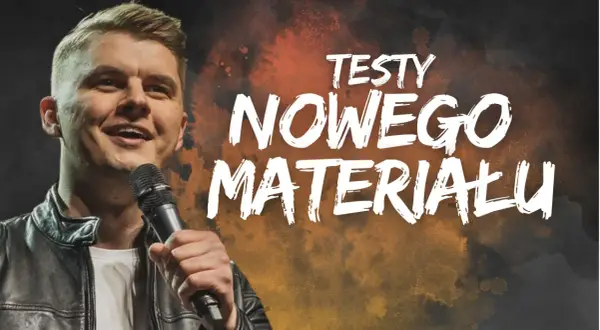 Uśmiechnięty komik na scenie, trzymający mikrofon. Na tle napis "TESTY NOWEGO MATERIAŁU".