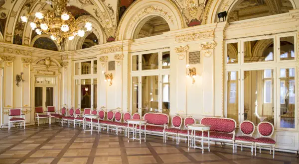 Eleganckie, złocone wnętrze z rzędami czerwonych foteli i stolików. To właśnie co to jest foyer w teatrze – miejsce spotkań przed spektaklem.