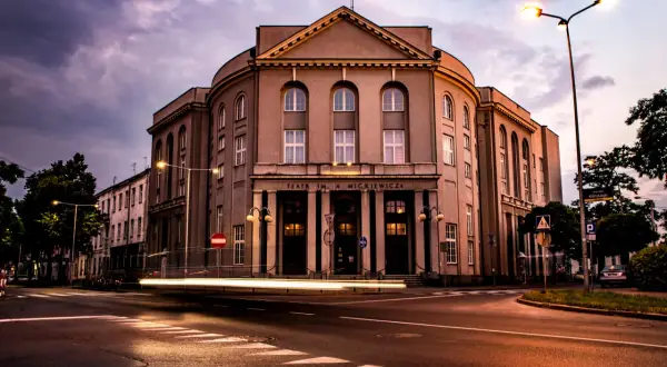 Teatr im. Adama Mickiewicza w Częstochowie nocą, z rozmazanymi światłami samochodów. Kto jest dyrektorem teatru w Częstochowie?