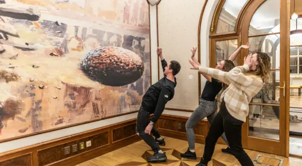 Trzech młodych ludzi w muzeum sztuki współczesnej w Pradze, wchodzących w interakcję z obrazem.