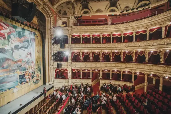 Widownia teatru w Krakowie, gdzie warto iść na spektakl. Złote zdobienia, czerwone aksamitne obicia i wielki malowany kurtyna tworzą magiczną atmosferę.