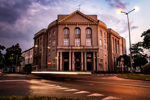 Teatr im. Adama Mickiewicza w Częstochowie nocą, z rozmazanymi światłami samochodów. Kto jest dyrektorem teatru w Częstochowie?
